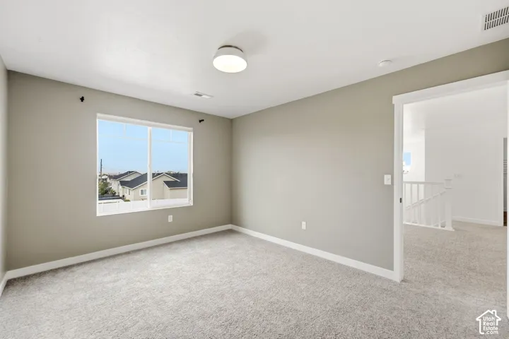 Neutral tone wall paint, carpet flooring, a large window, a white trim doorway, and a flush mount ceiling light