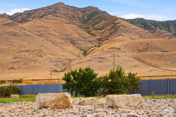 Expansive mountain backdrop, perimeter fencing, mature trees, and natural rock landscaping elements