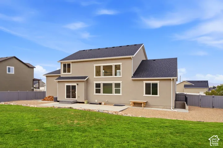Expansive green lawn, gravel landscaping, a concrete patio, and a privacy fence