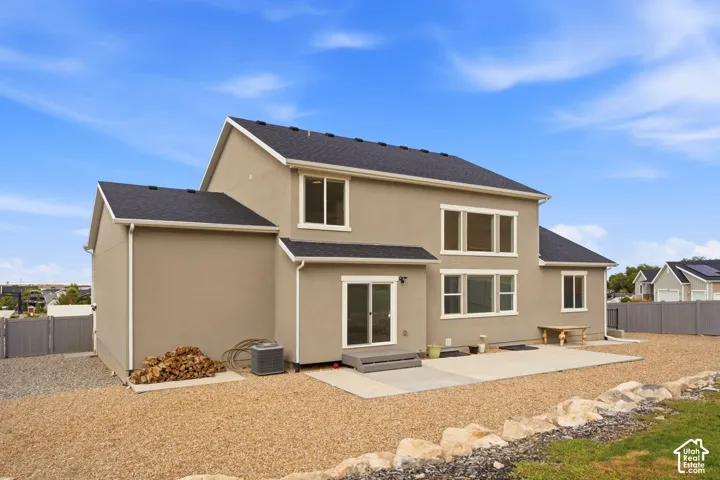 Stucco exterior with multiple windows, black shingle roof, and white trim