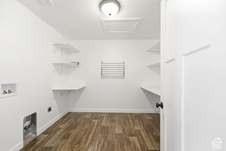 Dedicated utility space featuring wood-finish flooring, white walls, built-in shelving, and a wall-mounted drying rack