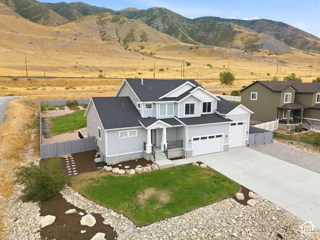 Contemporary residence featuring light gray siding, a dark shingle roof, a two-car garage, and a concrete driveway
