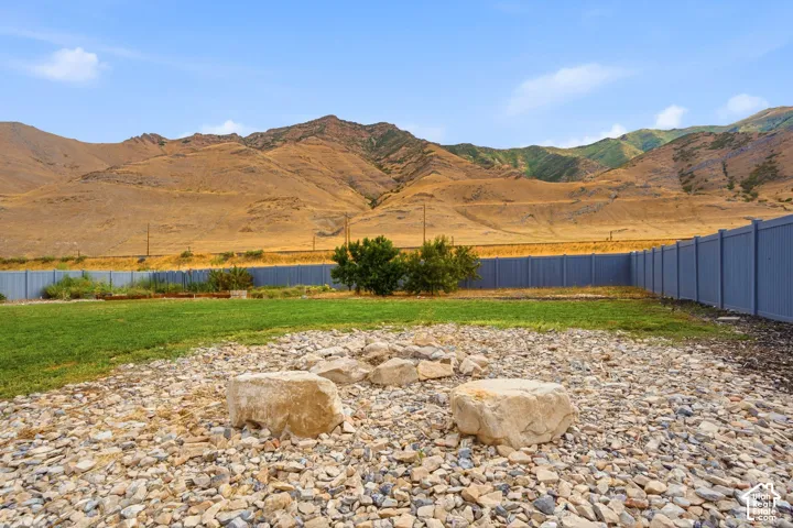 Expansive backyard featuring a gravel fire pit area with natural stone seating, a manicured lawn, and a privacy fence