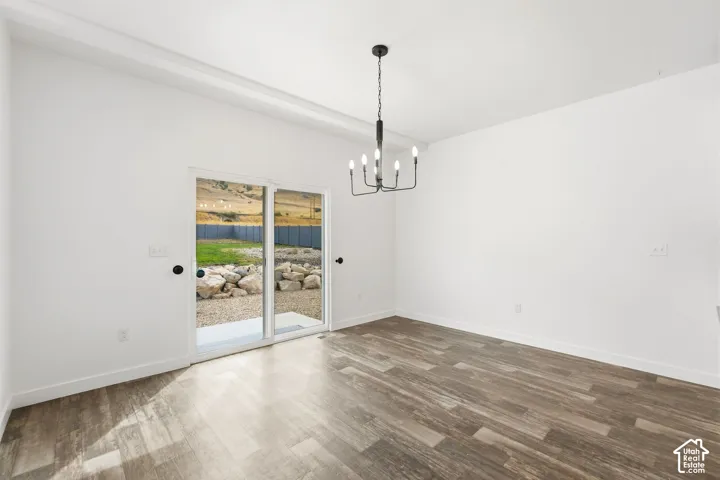 Spacious room with wood-finish flooring, white walls, and a contemporary chandelier