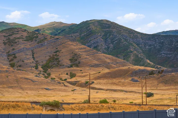 Expansive mountain backdrop with arid foothills, natural rock formations, and a clear blue sky