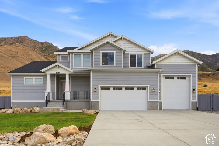 Contemporary exterior with horizontal siding, a covered porch with column details, a concrete driveway, and two garage doors