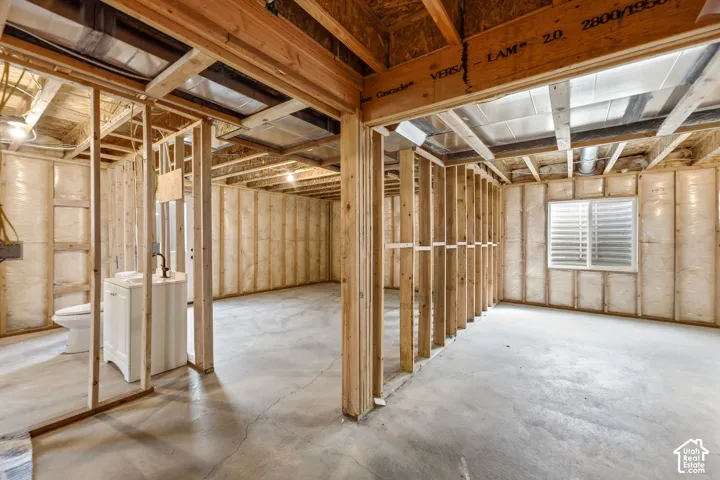 Spacious interior featuring exposed wood-beam ceiling with skylights, polished concrete flooring, and framed stall partitions with metal hardware