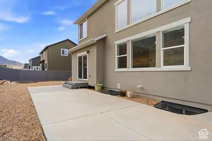 Rear exterior with a concrete patio, sliding glass door, white-trimmed windows, and a gravel landscape