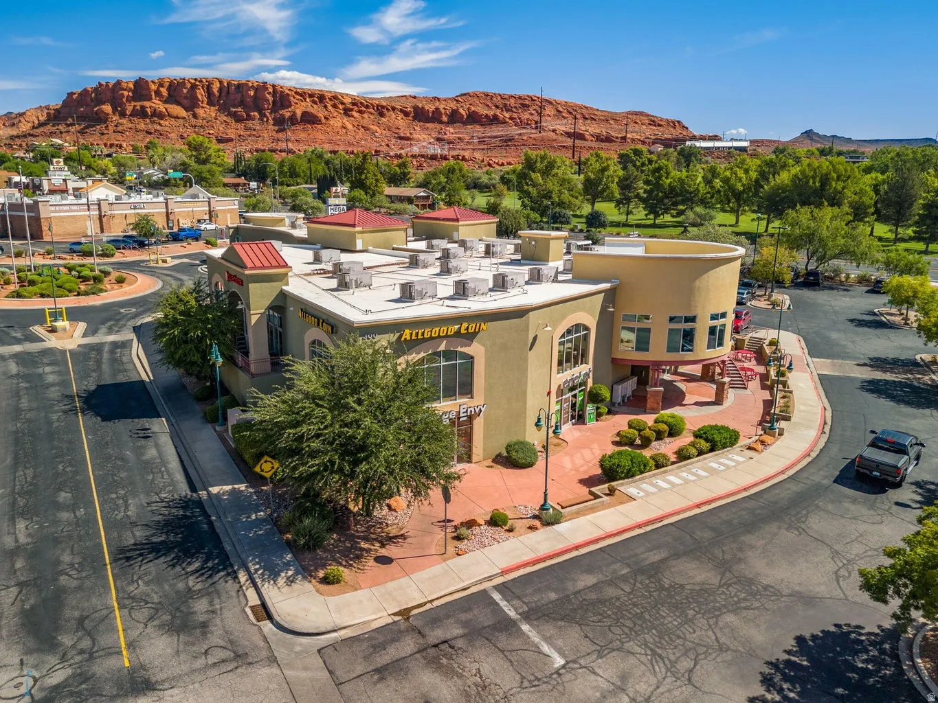 Multi-level commercial building featuring stucco exterior, red tile roof accents, arched windows, and a curved facade
