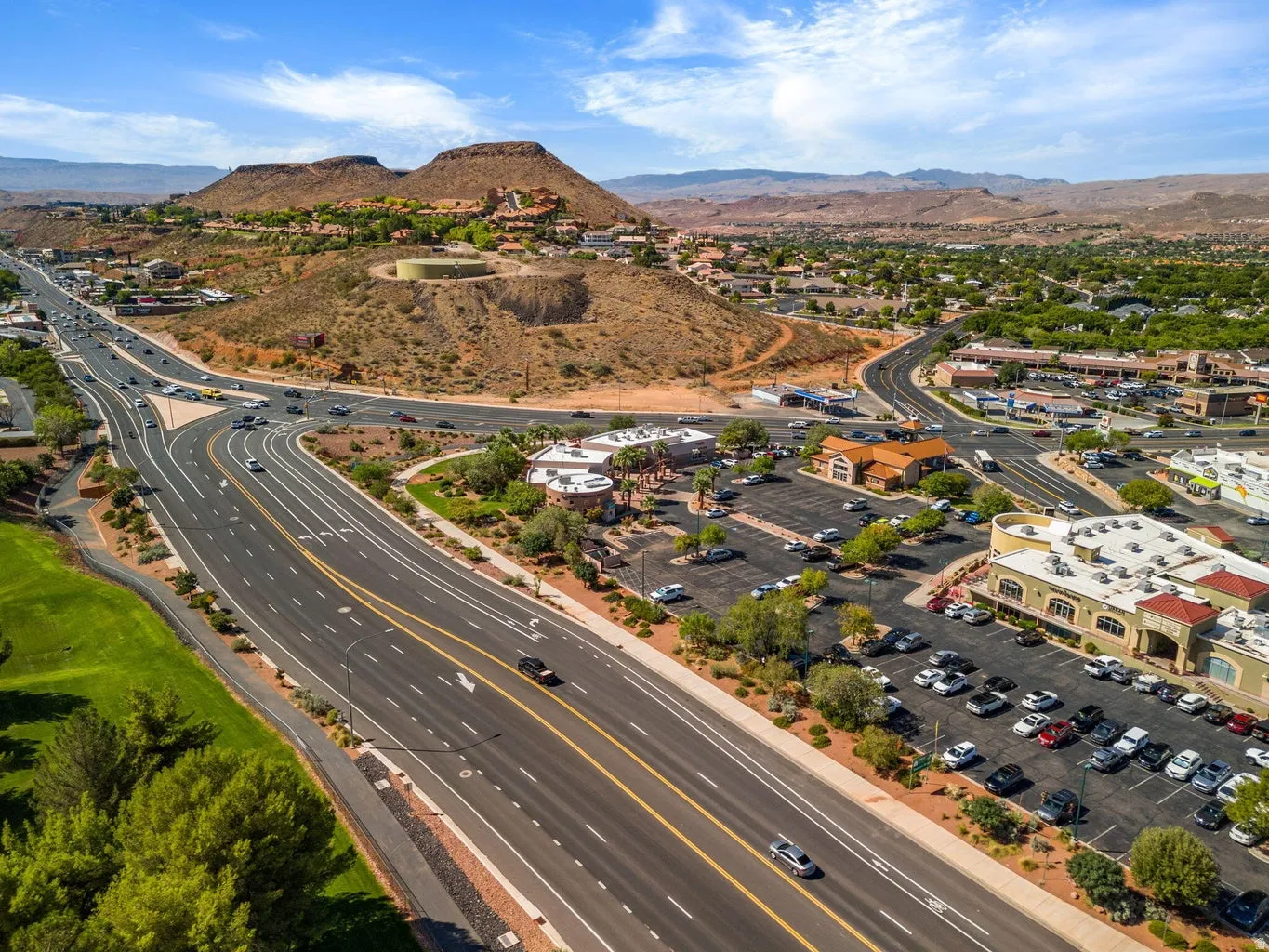 Aerial perspective of the surrounding area featuring established commercial properties, developed roadways, and distant natural terrain