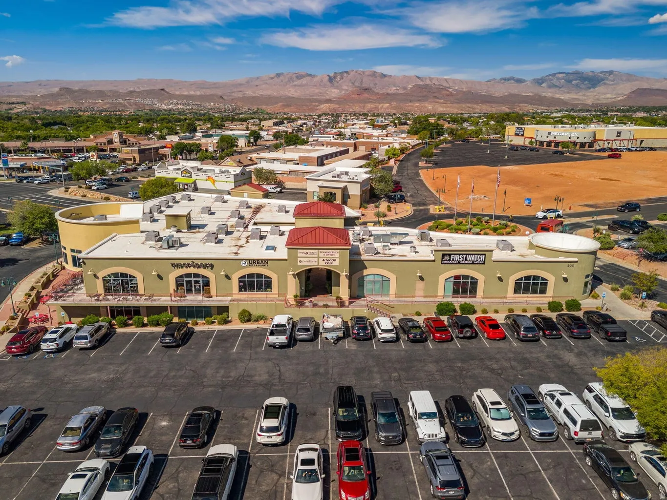 Commercial building with multiple storefronts, ample surface parking, and a prominent red tile roof