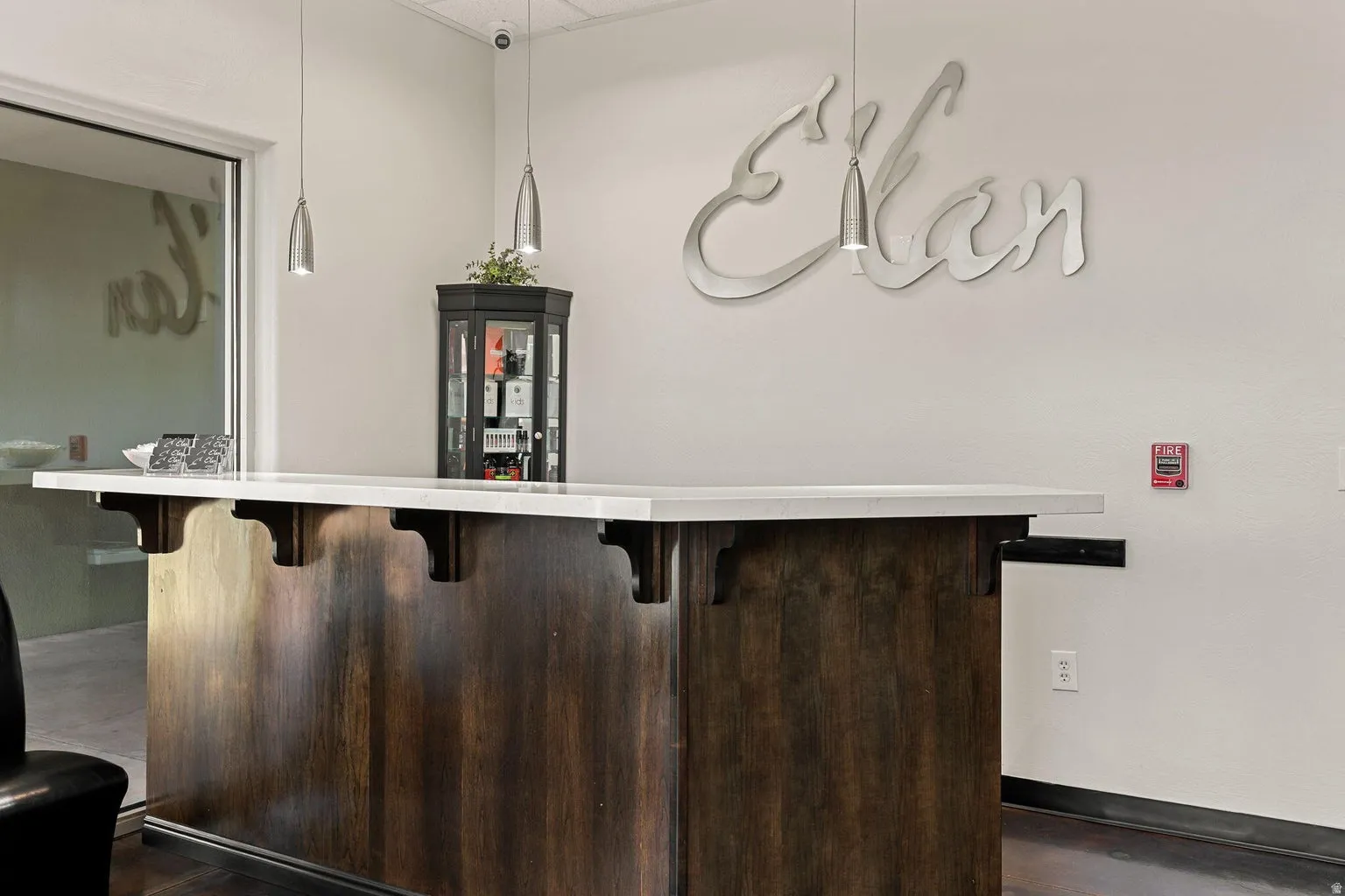 Dark wood-finish bar with a light-toned countertop, complemented by two pendant light fixtures