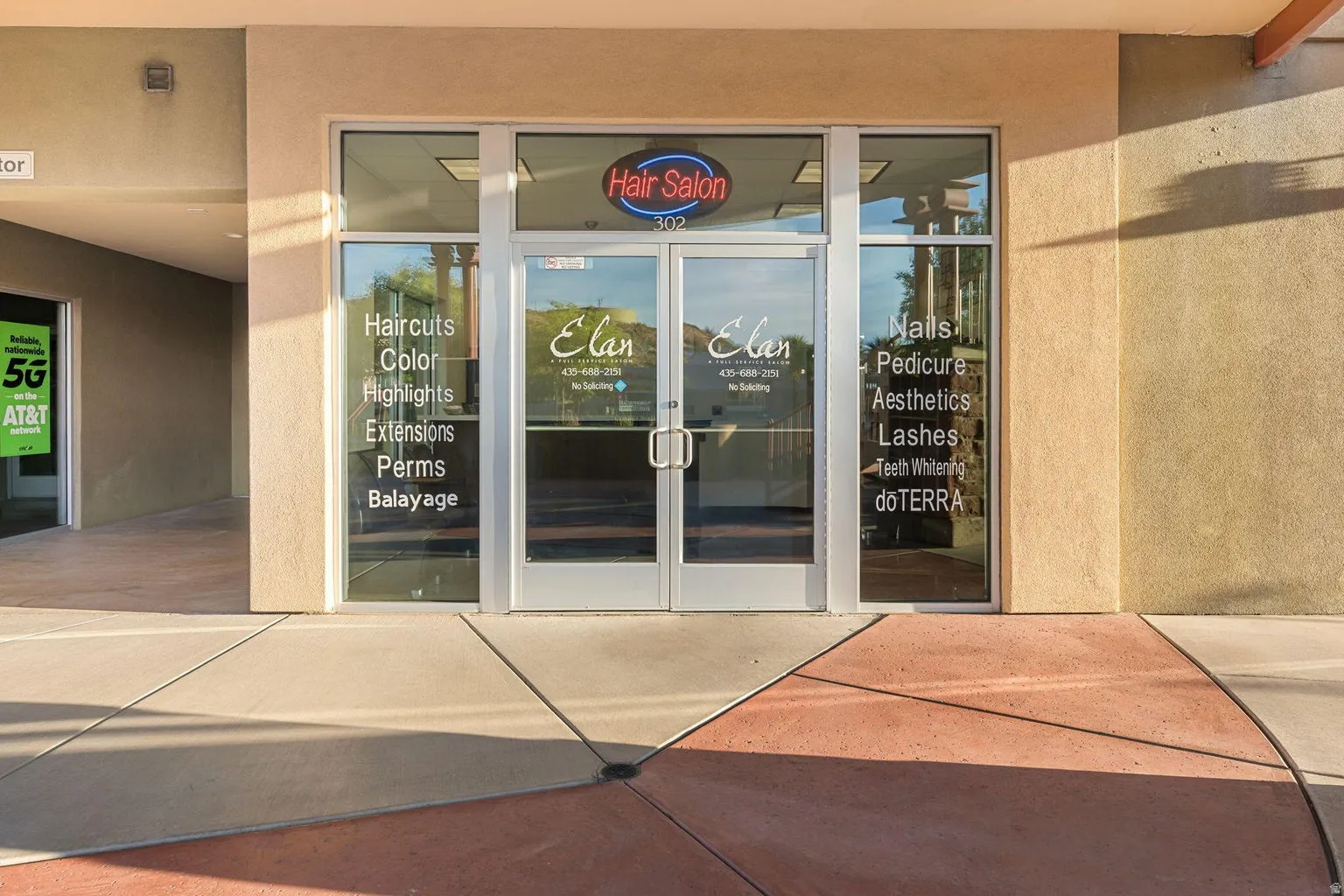 Storefront with dual glass entry doors, a neon business sign, and large display windows