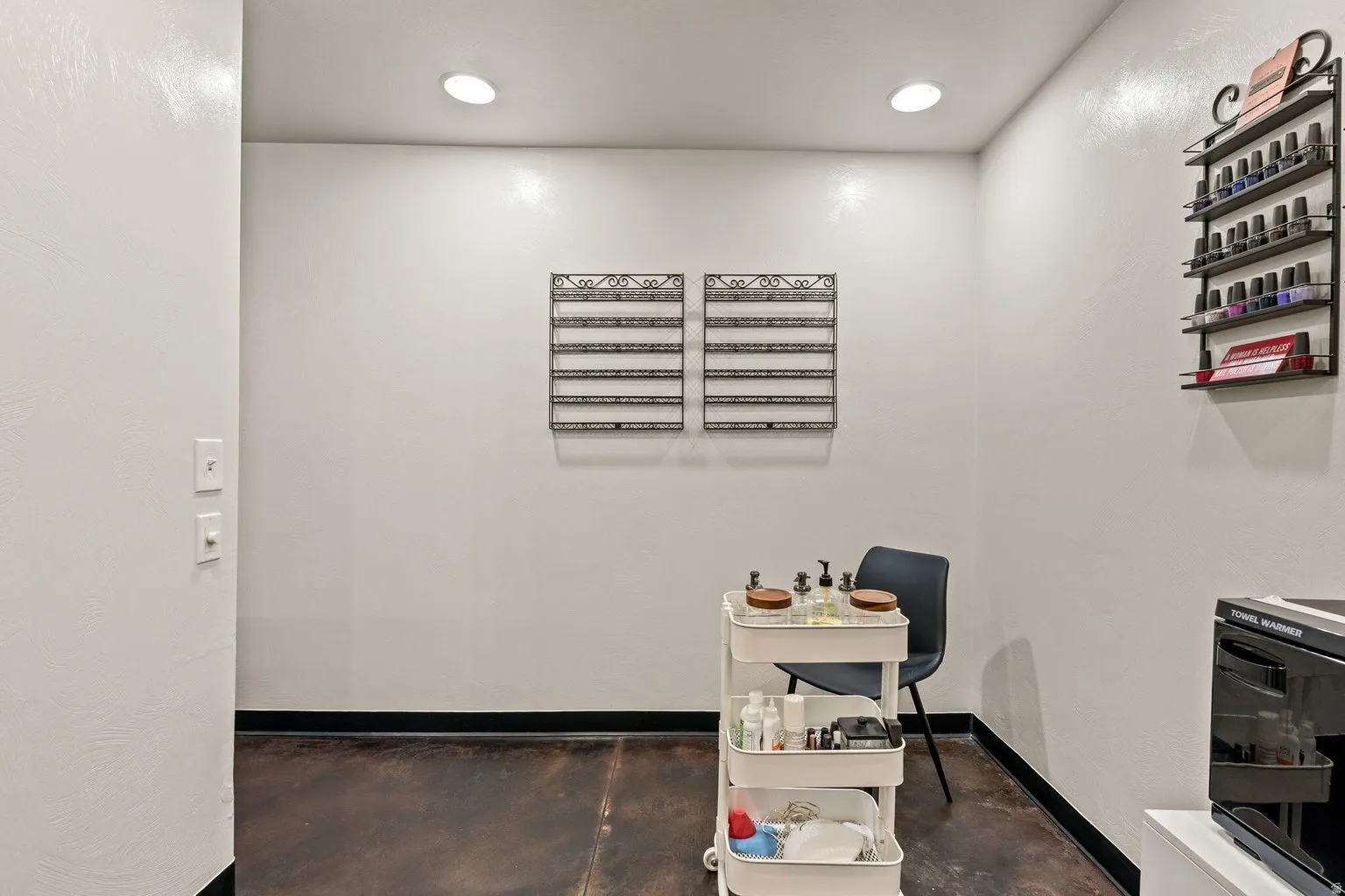 Recessed lighting illuminates a space featuring a dark-toned flooring and white walls