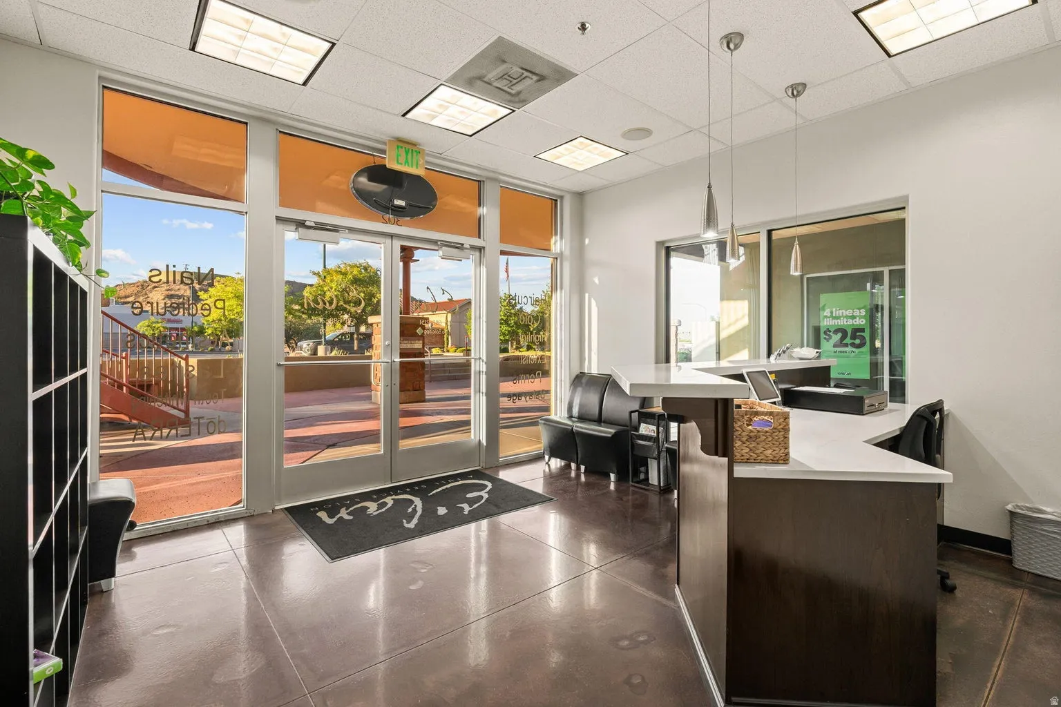 Glass entry doors, reception desk with white countertop, recessed lighting, and pendant lighting