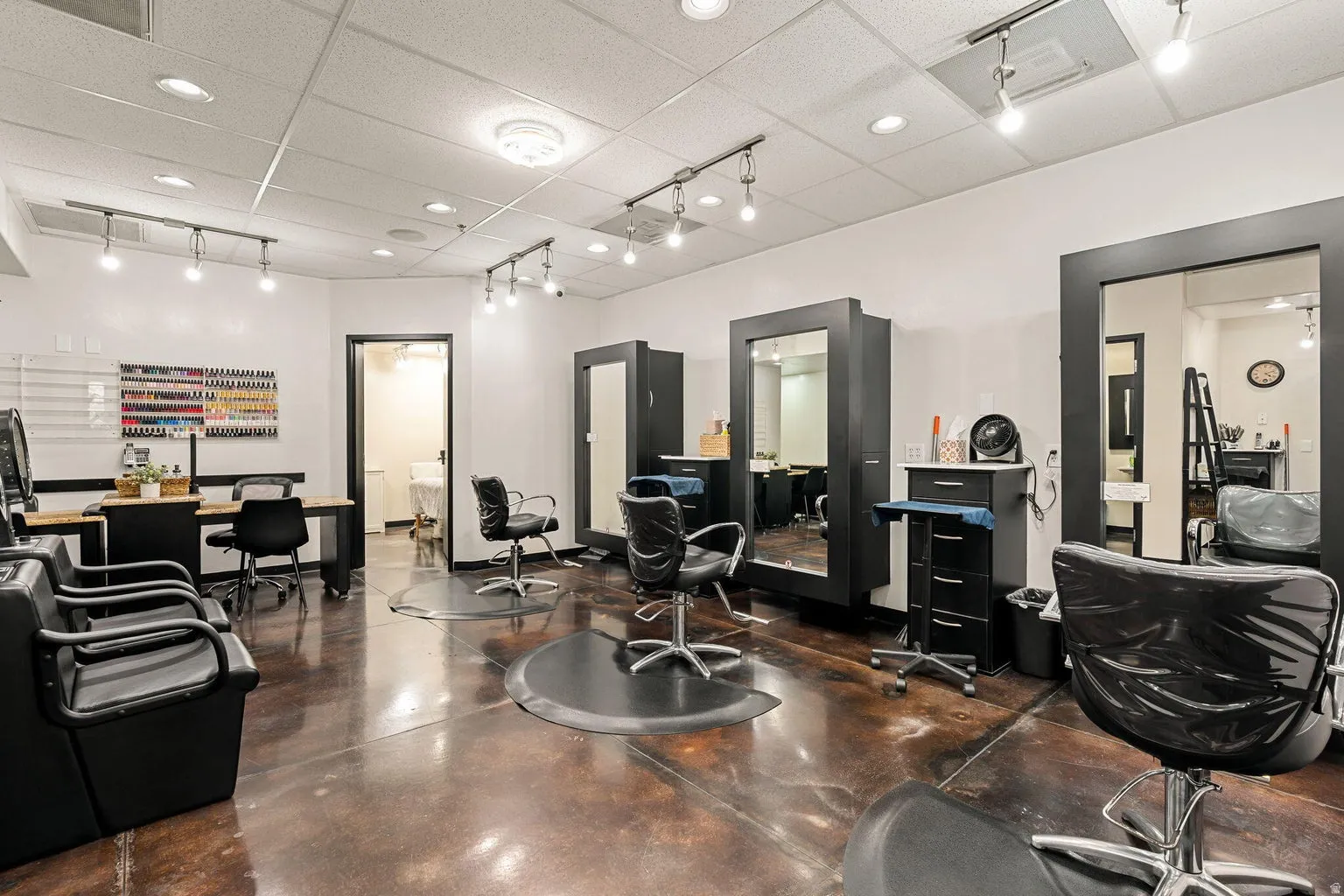 Polished concrete flooring, recessed lighting, track lighting, white walls, and a black framed doorway