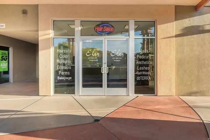 Storefront with dual glass entry doors, a neon business sign, and large display windows