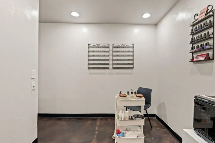 Recessed lighting illuminates a space featuring a dark-toned flooring and white walls