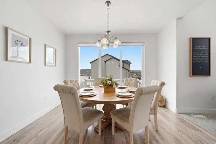 Spacious dining area featuring wood-finish flooring, a contemporary chandelier, and a large window