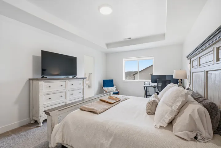 Tray ceiling with recessed lighting, wall-to-wall carpeting, and a window providing natural light