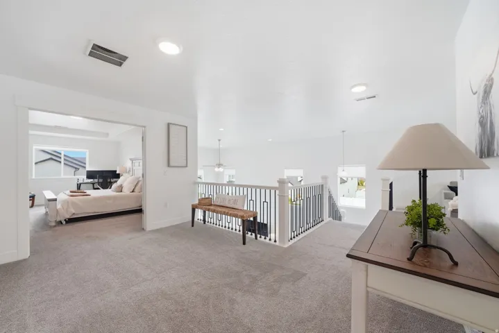 Carpeted loft area with recessed lighting, white balusters, and black metal spindles