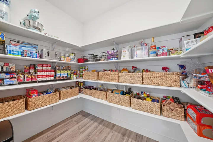 Expansive pantry featuring multi-level shelving, wood-finish flooring, and white wall paneling