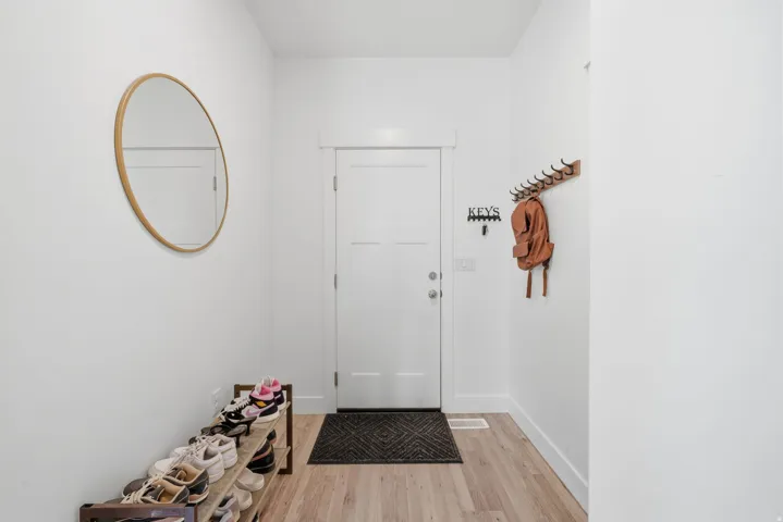 Entryway featuring a solid panel door, wood-finish flooring, and a wall-mounted coat rack