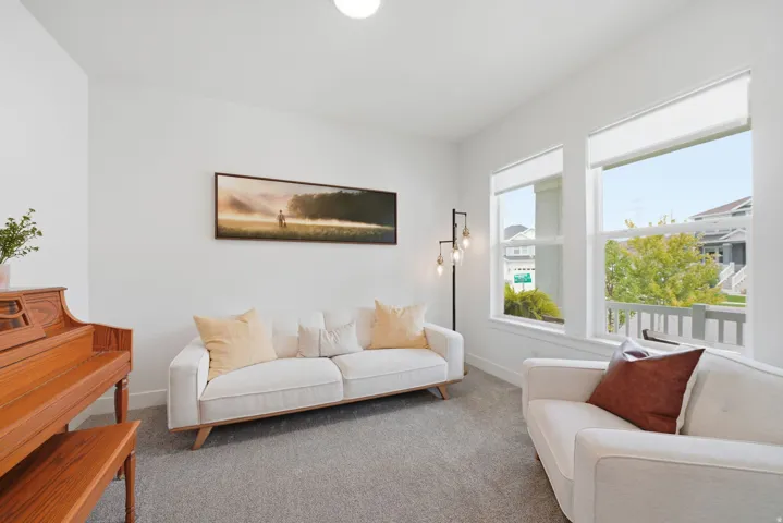 Bright interior room featuring multiple windows, neutral wall tones, and carpet flooring