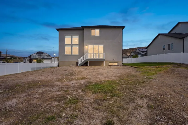 Stucco exterior with multiple windows, a white deck with railings, and a fenced backyard