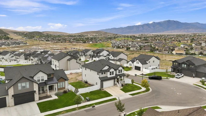 Residential neighborhood featuring modern two-story homes with attached garages, manicured lawns, and a distant mountain backdrop