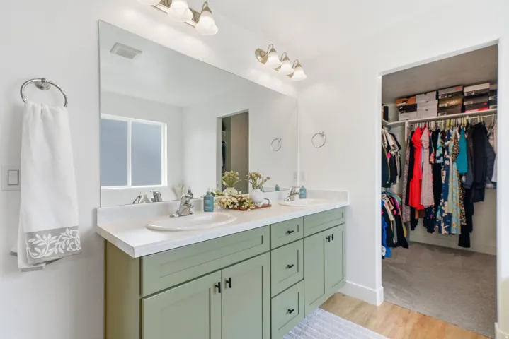 Dual vanity with light-toned countertop, integrated sinks, and green cabinetry