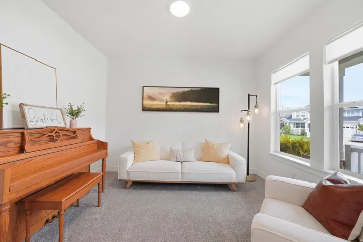 Bright interior space featuring light gray carpeting, crisp white walls, and multiple windows