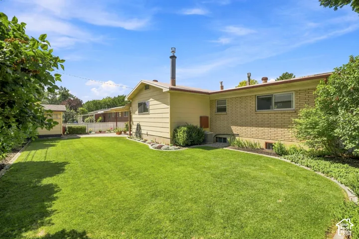 Expansive lawn with defined landscaping borders, a storage shed, and a main structure featuring both siding and brick exterior finishes