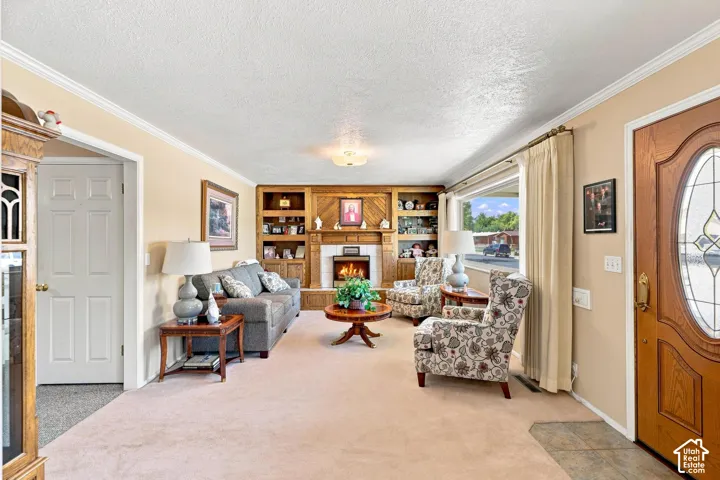 Wood-paneled fireplace surround with a white mantle, built-in shelving, front entry door with an oval leaded glass insert, and a large front window