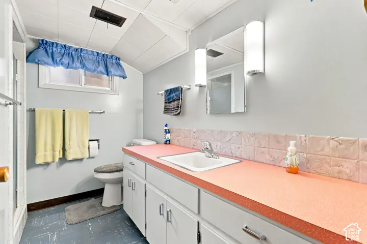 Bathroom featuring a single basin vanity with extensive countertop space, wall-mounted mirror, and overhead lighting