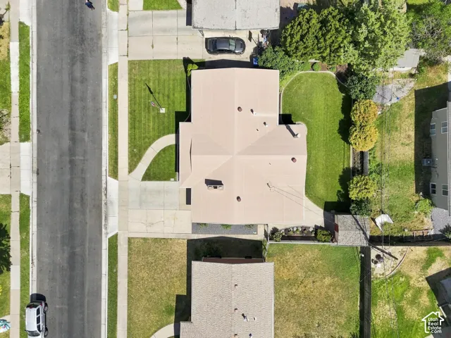 Property with a light-toned roof, paved driveway, and a front lawn with a curved walkway