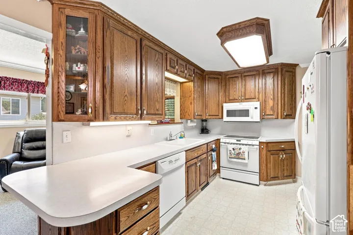 Kitchen featuring wood-finish cabinetry, solid surface countertops, a built-in microwave, and a white appliance package