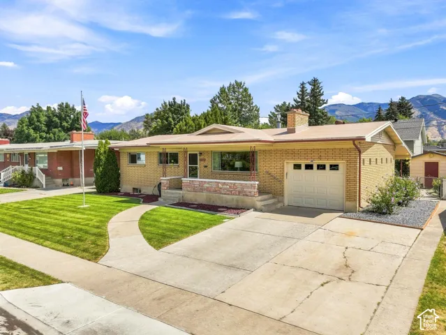 Brick exterior with a single-car garage, mature landscaping, and a concrete driveway
