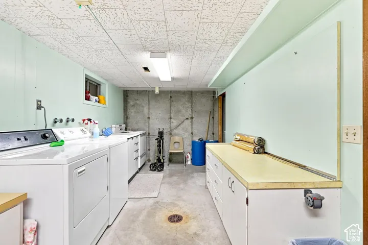 Laundry area with drop ceiling, concrete flooring, and built-in white cabinetry with light-toned countertops