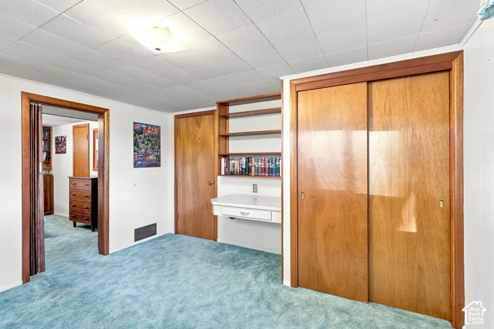 Built-in shelving, built-in desk, wood-panel sliding closet doors, wood-panel interior door, and textured ceiling panels