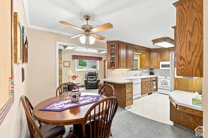 Spacious kitchen and dining area featuring wood cabinetry, white appliances, ceramic tile flooring, and a ceiling fan with integrated lighting