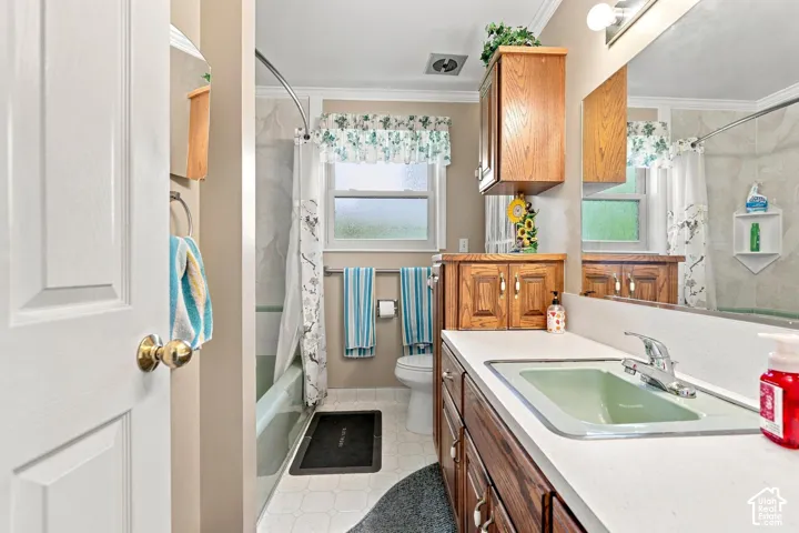 Bathroom featuring a wood-finish vanity with a light green integrated sink, a matching wall-mounted cabinet, and a tiled shower-tub combination