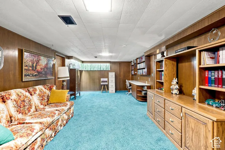 Wood-paneled walls with built-in shelving, a dedicated desk area, recessed lighting, and a window