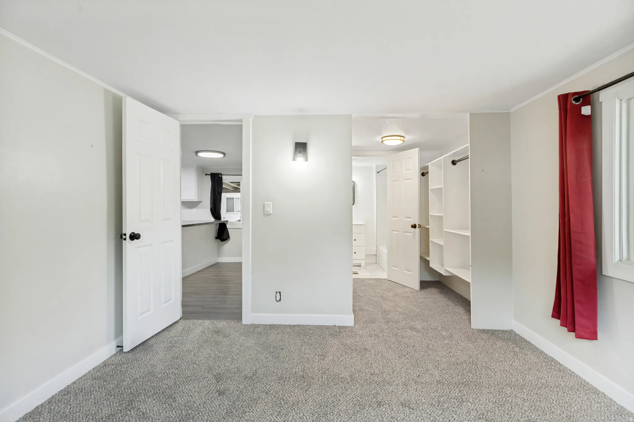 Neutral gray wall paint with white trim, gray carpet, built-in closet shelving, and a wall-mounted sconce