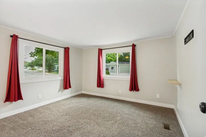 Bright corner room with dual windows framing natural light, neutral wall finishes, and neutral carpeting throughout