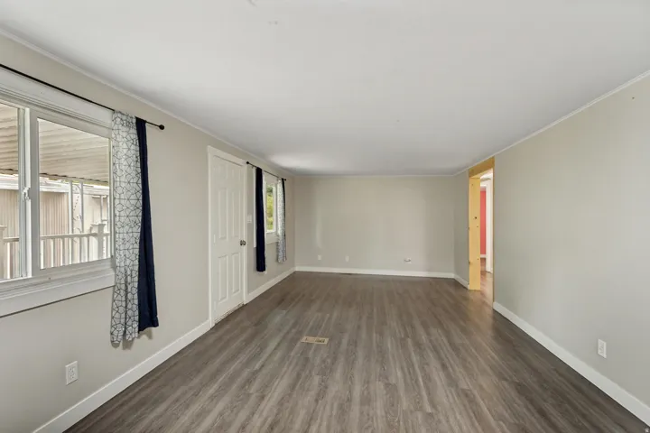 Spacious interior room with wood-finish flooring, light-toned walls, and multiple windows