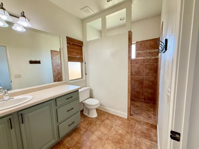 Bathroom featuring a single vanity, integrated sink, and an enclosed shower with tile surround