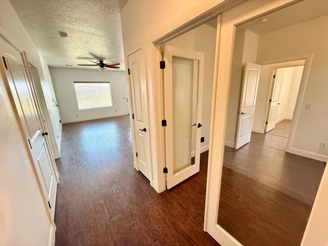 Wood-finish flooring throughout, white paneled doors with matte black hardware, a ceiling fan, and a large window