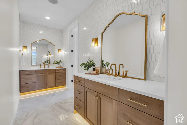 Dual wood-finish vanities with undermount sinks, white countertops, and brass hardware