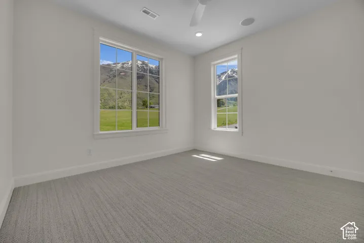 Bright room with two windows, textured carpet, recessed lighting, and a ceiling fan